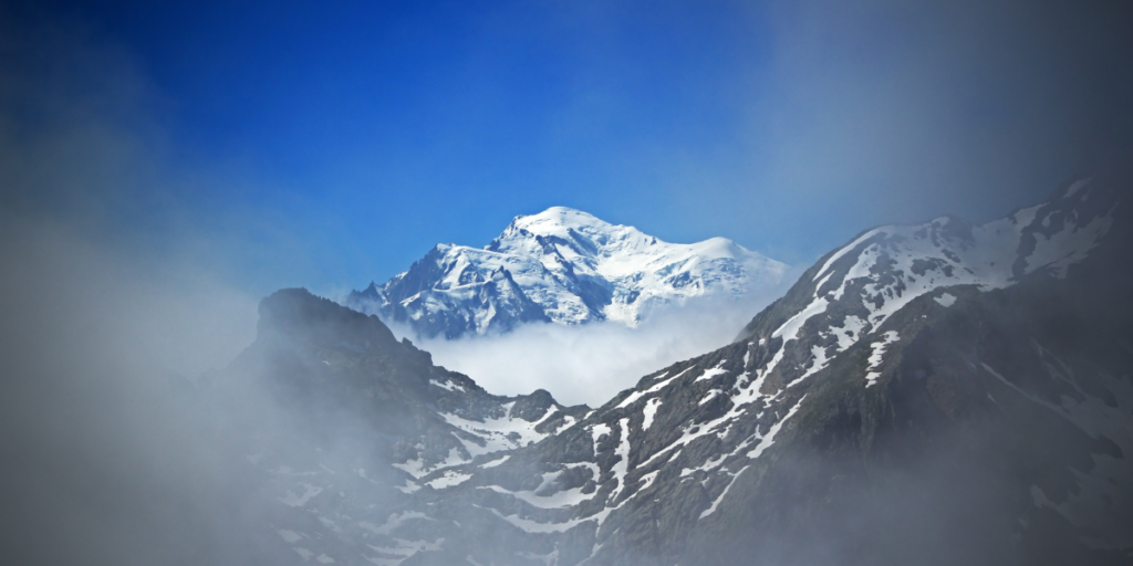 le Mont Blanc émergeant d'une mer de nuages avec des sommets enneigés en arrière-plan.