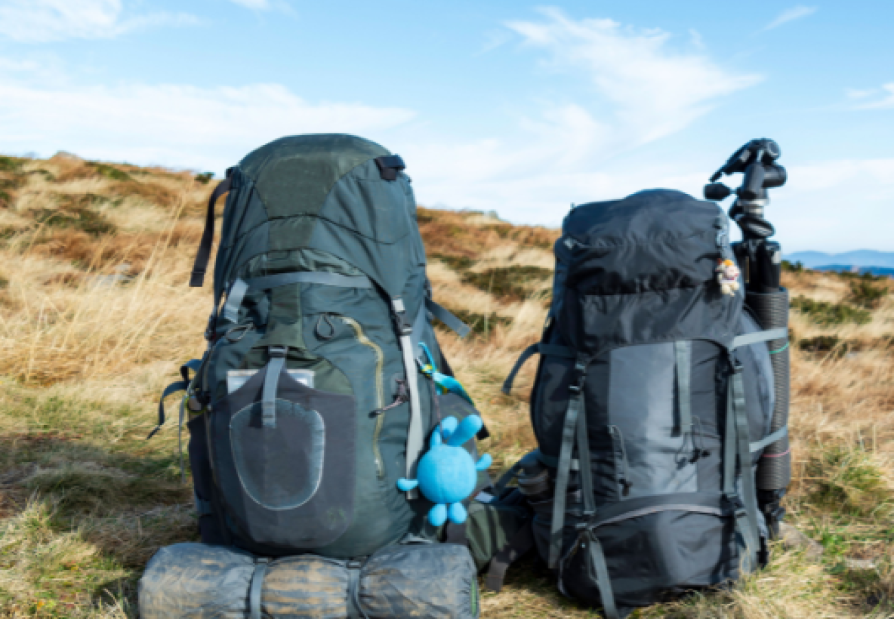 Sac à dos de randonnée rouge avec tente de camping fixée en forêt, équipement de bivouac