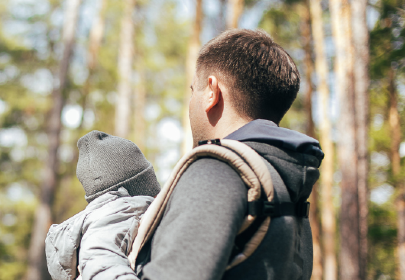 Homme portant un enfant avec un sac à dos ergonomique en pleine nature
